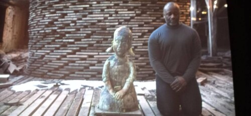 Image tirée de la vidéo A clay Sermon : Theaster Gates assis à côté d'une petite fille en terre