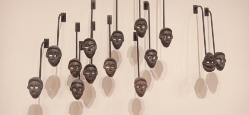 Installation par Theaster Gates : masques accrochés à un mur blanc